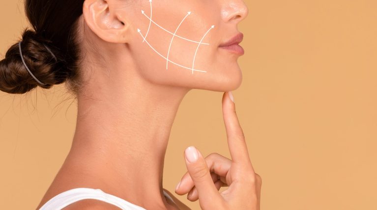 Lady touching chin, lifting arrows showing facial anti-aging treatment on skin, panorama, free space Profile of young woman with clean fresh skin, antiaging concept. Lady touching chin, lifting arrows showing facial anti-aging treatment on skin, panorama, free space