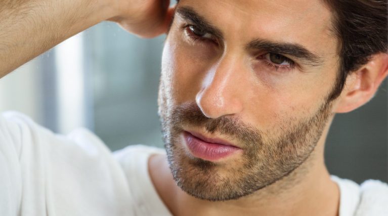 Close-up of young man checking his hair in bathroom