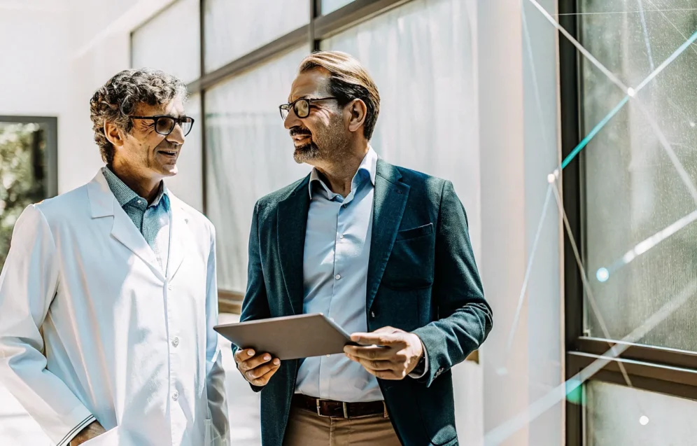 benefits-of-testosterone-therapy-a-complete-guide-183464 A doctor explains the benefits of testosterone therapy to a man using a tablet.